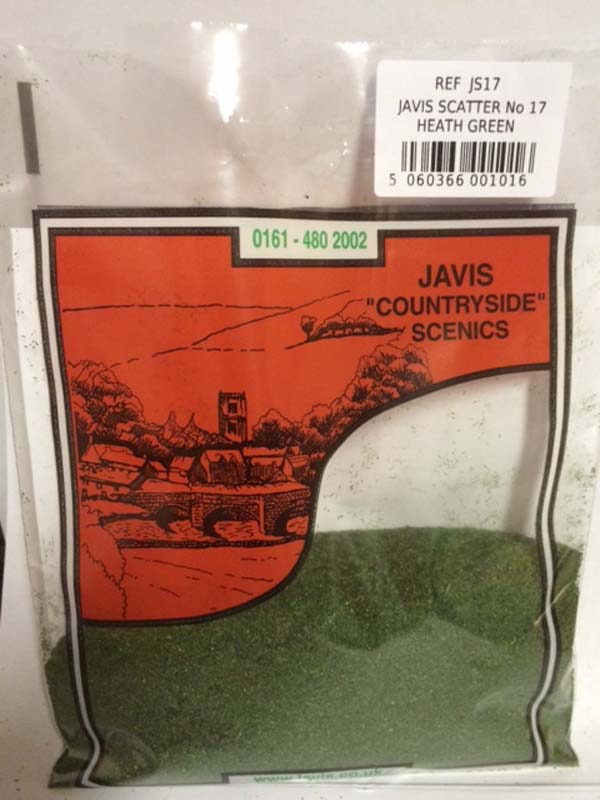 A bag of Javis 'Countryside' Scenics  JS17 Heath Green model scenery scatter, showing the green granules through a clear window in the packaging, with an orange landscape illustration and a white product reference label.