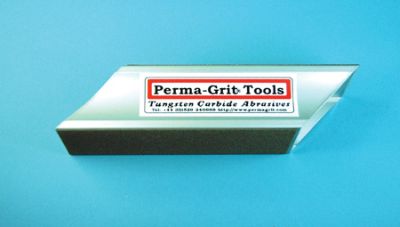 A rectangular Perma-Grit Tools tungsten carbide abrasive tool with a silver metallic face and a black base, shown on a solid blue background.