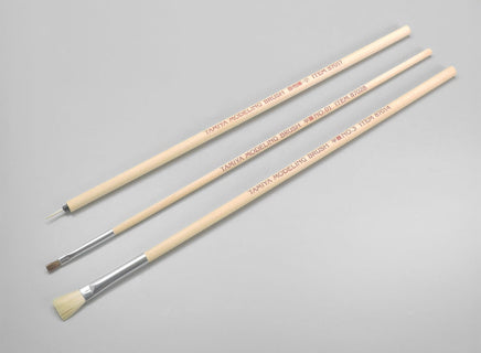 Three paintbrushes of different sizes on a grey background