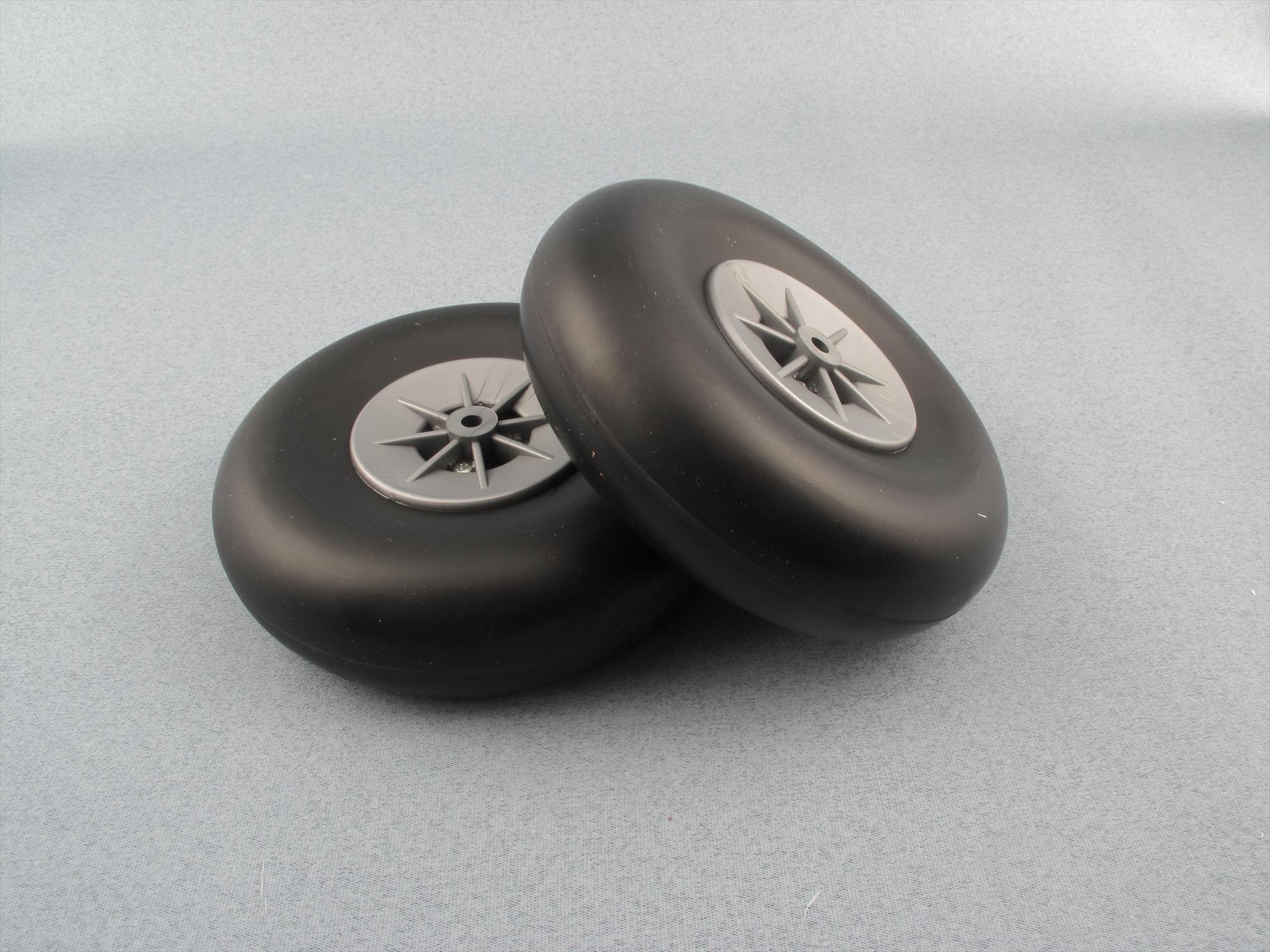 Two black airwheels  with grey nylon hubs  photographed on a plain light grey surface.