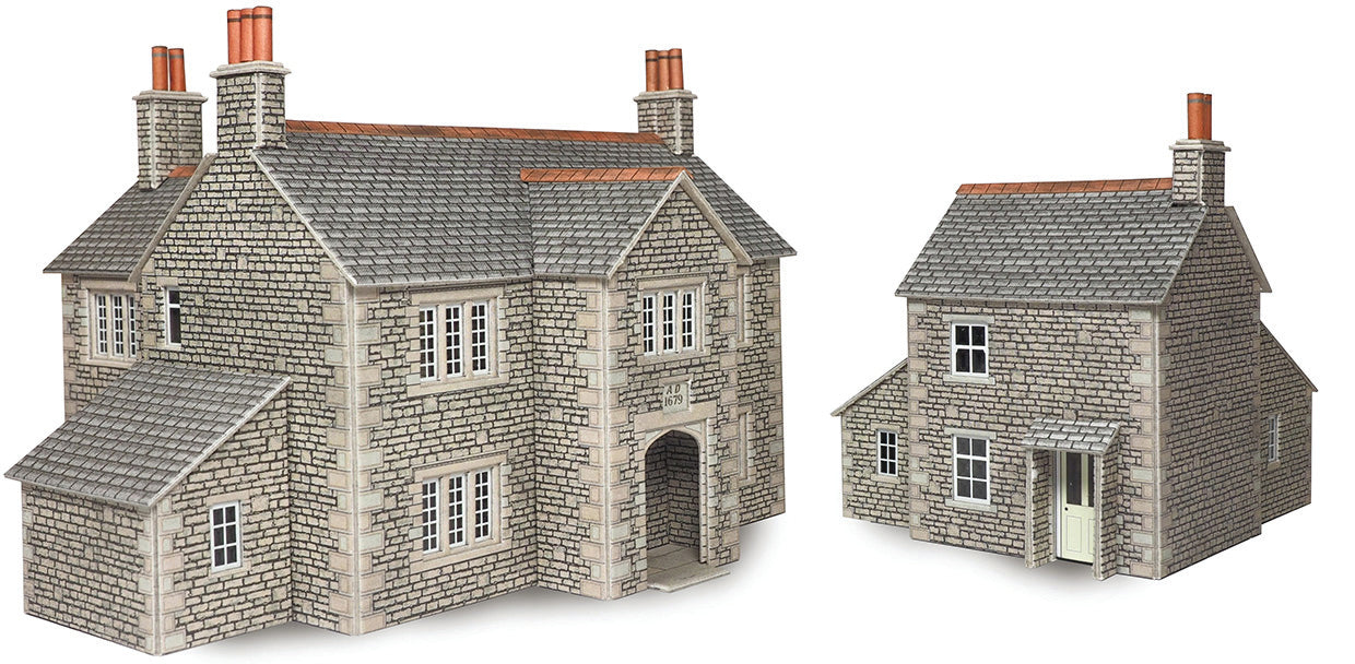 A model house and cottage  on a plain white background. The building has grey stone walls, a grey tiled roof, orange-brown chimneys, and a small white door.
