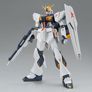 Model kit of a mecha with white, gray, and blue colour scheme in a dynamic pose with gun and large shield on a gray background