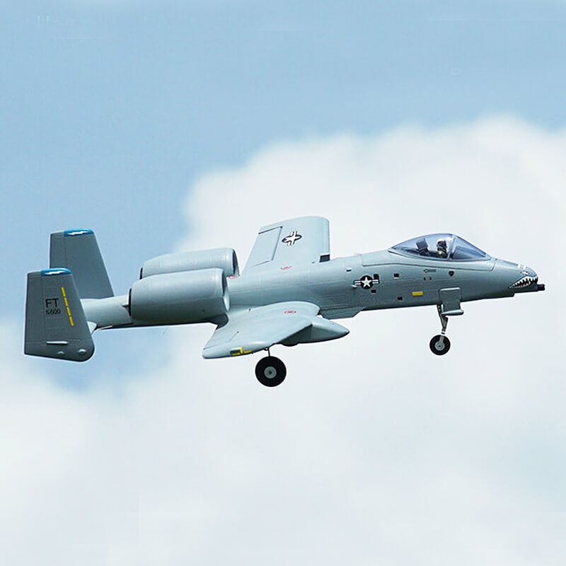 Gray military aircraft flying against a blue sky with white clouds